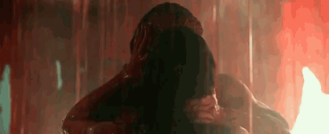a close up of a person covered in blood in a shower with a fire in the background .