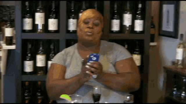 a woman is holding a cell phone in front of a shelf full of wine bottles