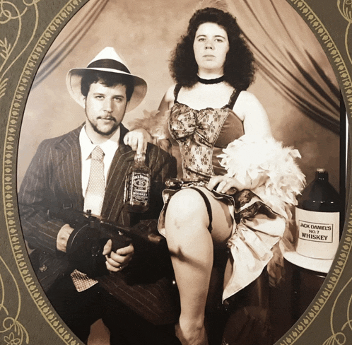 a man holding a gun and a woman holding a bottle of jack daniels