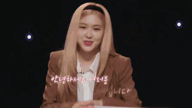 a woman with blonde hair is wearing a brown jacket and a headband and making a funny face .