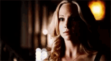 a woman is looking at the camera in a dark room .