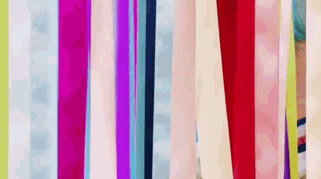 a woman with blue hair is standing behind a row of colorful striped ribbons .