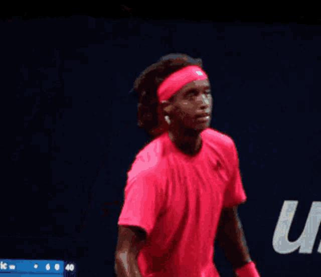 a man in a red shirt is holding a tennis racquet in front of a sign that says rajinovic