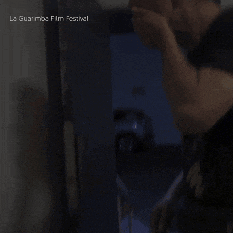 a man covering his mouth in a dark room with the words la guarimba film festival on the bottom