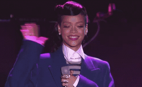 a woman in a blue suit and white shirt is holding a microphone .
