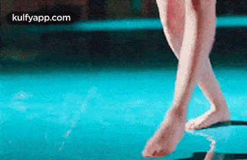 a woman 's feet are walking on a blue surface .