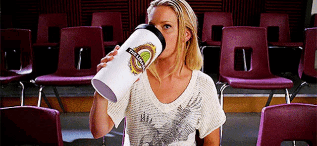 a woman is drinking from a white cup that says " the team " on it