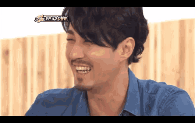 a man with a beard wearing a blue shirt is laughing