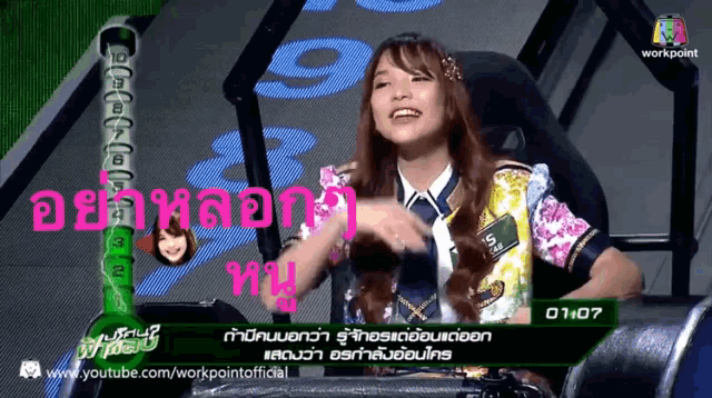 a woman sitting in front of a screen that says 1:07 on it