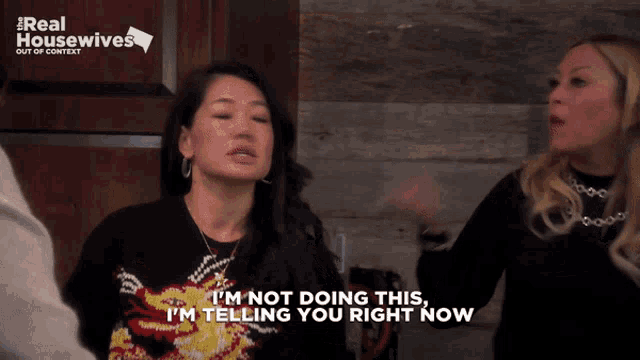 a woman says i 'm not doing this i 'm telling you right now in front of a real housewives sign