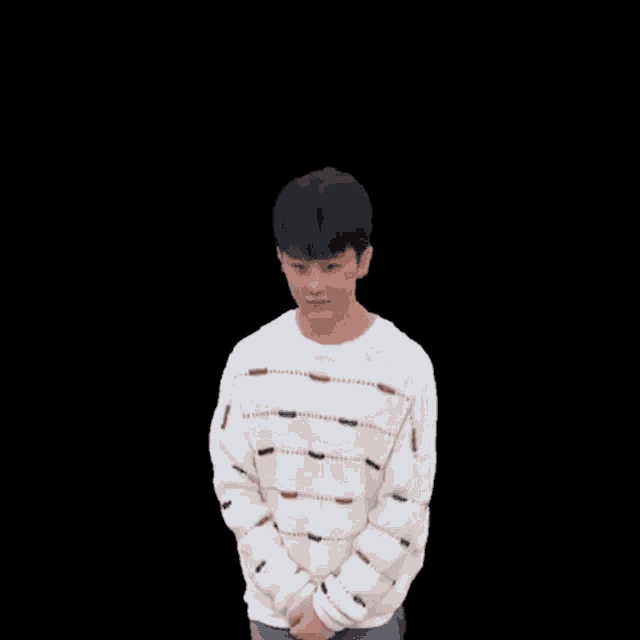 a young man wearing a striped sweater is raising his arms in the air
