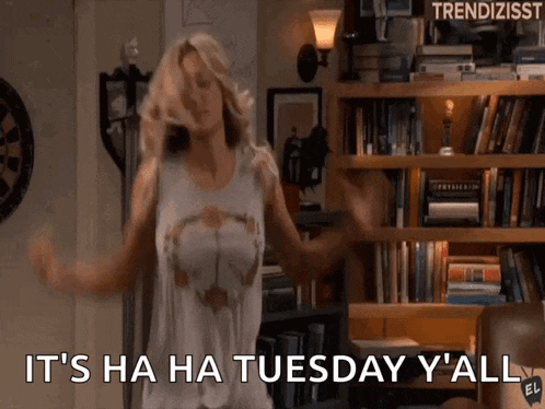 a woman is dancing in front of a bookshelf and says it 's ha ha tuesday y 'all