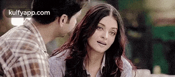 a man is kissing a woman on the cheek while they are sitting next to each other .