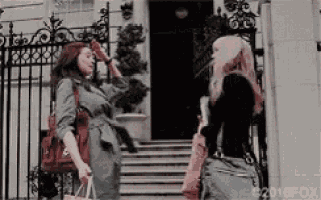 two women are standing on a set of stairs in front of a building .