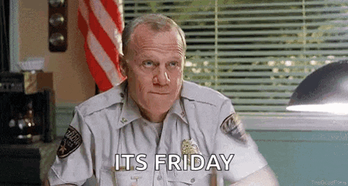a man in a police uniform is sitting at a desk in front of a window and says `` its friday '' .