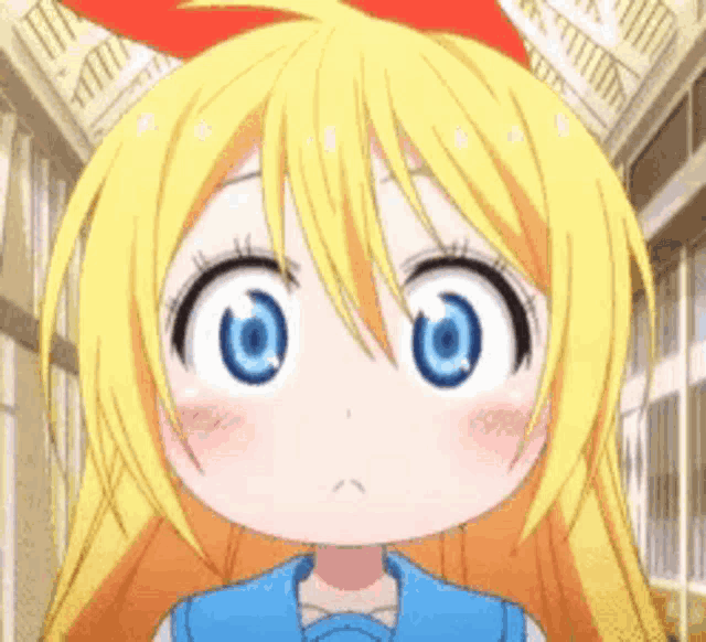 a little girl with blonde hair and blue eyes is wearing a blue shirt and a red bow on her head .