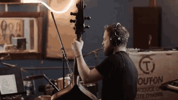 a man wearing headphones is playing a double bass in front of a sign that says " wouton "