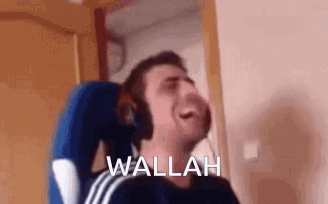 a man wearing headphones is sitting in a chair with the word wallah written on the bottom of his face .