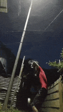 a man in a red shirt is climbing a pole