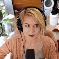 a woman wearing headphones and red lipstick is looking at the camera