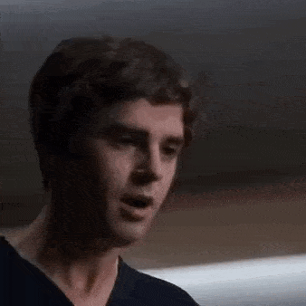 a close up of a man 's face with his mouth open and his eyes closed in a dark room .