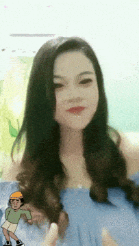 a woman in a blue off the shoulder top is smiling with a cartoon character behind her