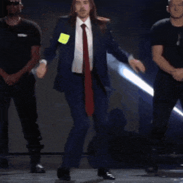 a man in a suit and tie is dancing with two men