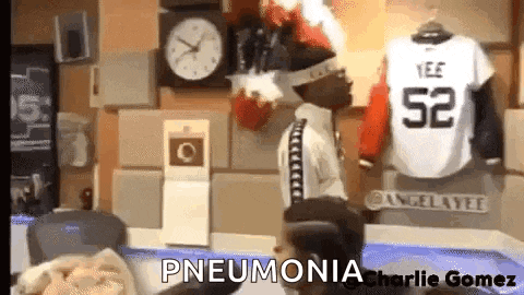 a man is standing in front of a clock and a jersey that says pneumonia on it .