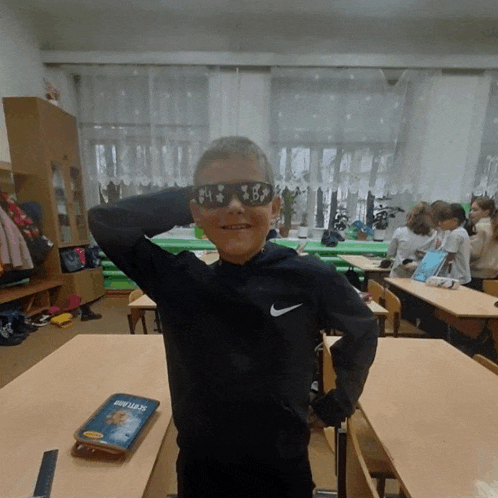 a boy wearing under armour sunglasses stands in front of a book called steelman