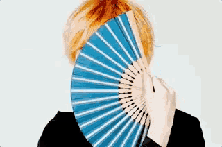 a woman covering her face with a fan