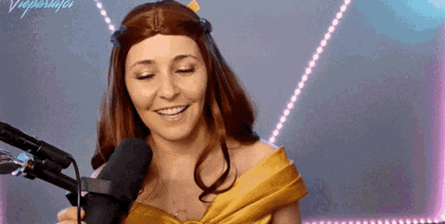 a woman in a beauty and the beast costume is smiling into a microphone