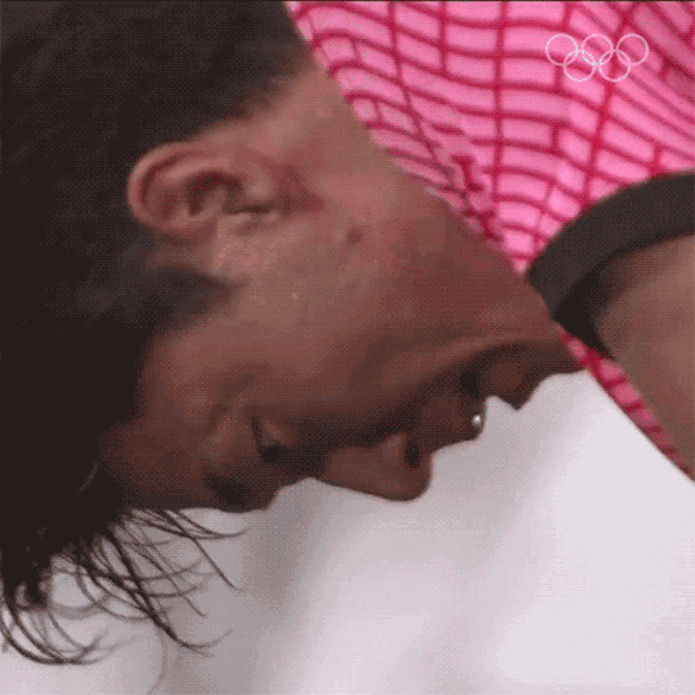 a close up of a person 's face with the olympic rings on the bottom right