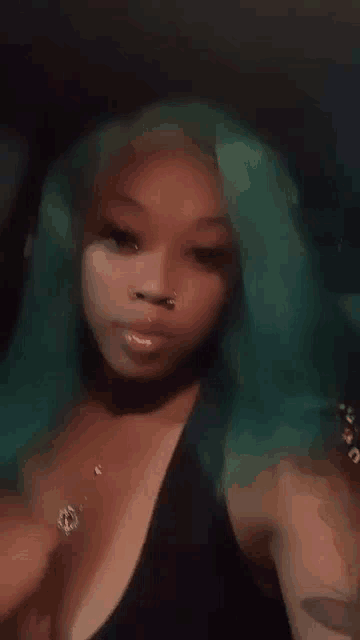 a woman with green hair and a nose ring is taking a selfie .