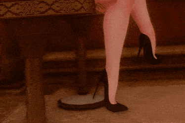 a woman sitting on a stool with her legs crossed and a tattoo on her leg