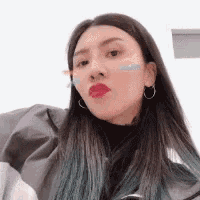 a woman with long hair and earrings is taking a selfie with a sticker on her face .