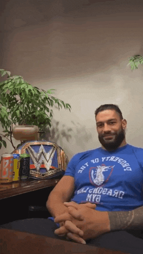 a man wearing a blue shirt that says " just 40 yards away " sits at a table