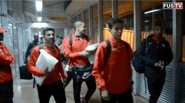 a group of men are walking down a hallway with the word fustv on the bottom