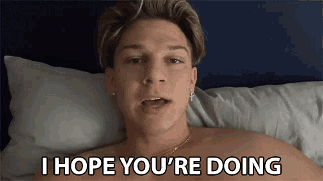 a shirtless man is laying on a bed with the words i hope you 're doing written above him