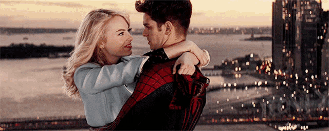 a man is holding a woman in his arms in front of a city skyline