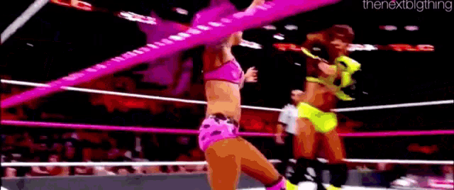 two women are wrestling in a ring with a pink rope .