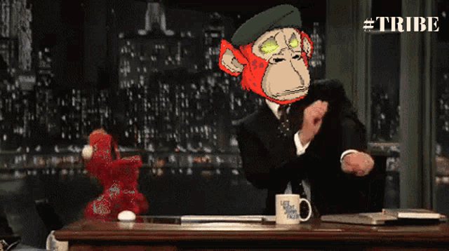 a man with a monkey on his head sits at a desk with a cup that says late night talk show