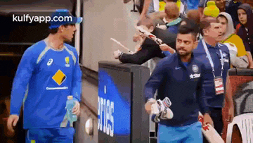 a man in a blue shirt is walking with a bat in his hand .