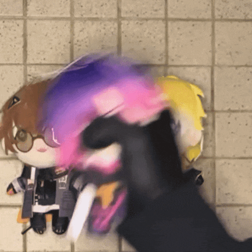 a person is holding a stuffed animal with glasses and a purple and pink hair ..