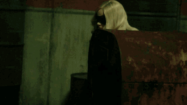 a blonde woman wearing a black mask and a black outfit