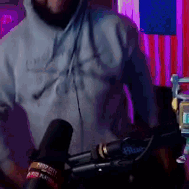 a man wearing a grey hoodie is standing in front of a microphone ..