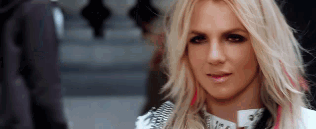 a close up of a woman 's face with blonde hair and pink streaks