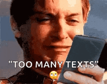 a man is crying while holding a cell phone and says `` too many texts '' .