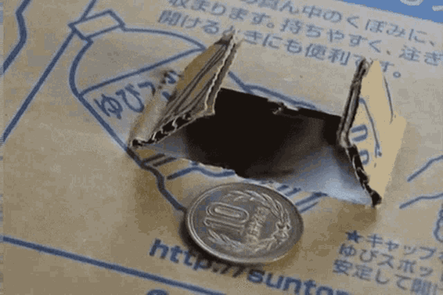 a coin sits on top of a cardboard box that says http:// suntory