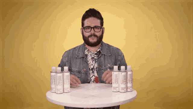 a man in a denim jacket is standing in front of a table with bottles of lube life