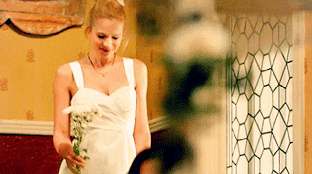 a woman in a white dress holding a bouquet of flowers